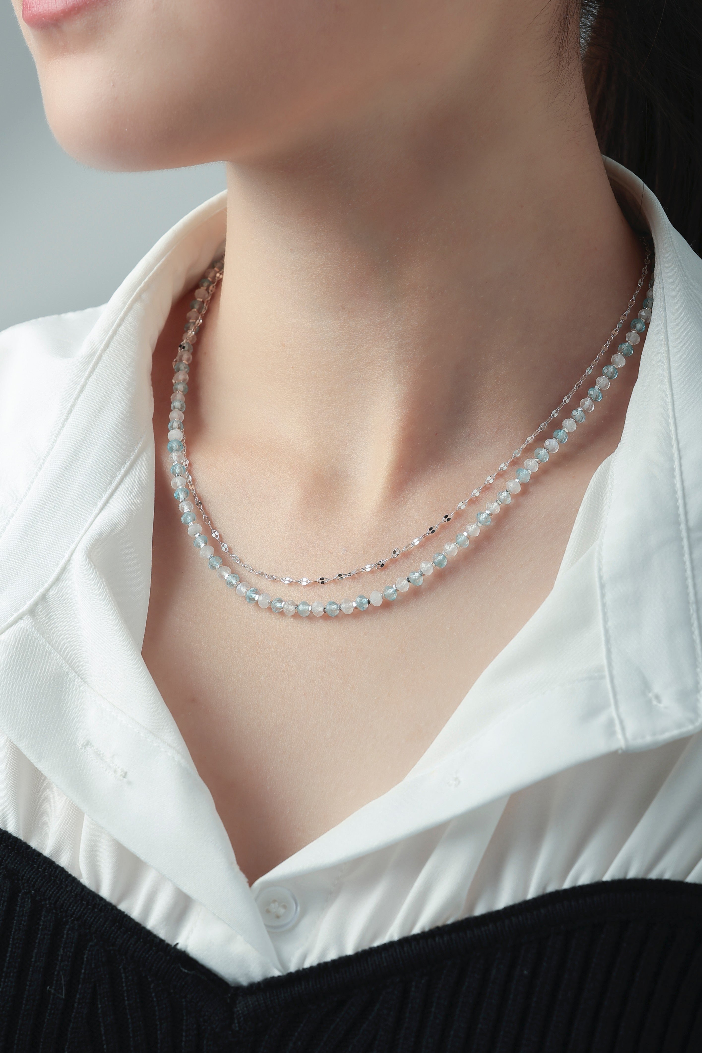 アクアマリン 2連ネックレスの着用イメージ。白シャツの襟元から覗く、涼やかなブルーとシルバーチェーンの重ね付けスタイル。