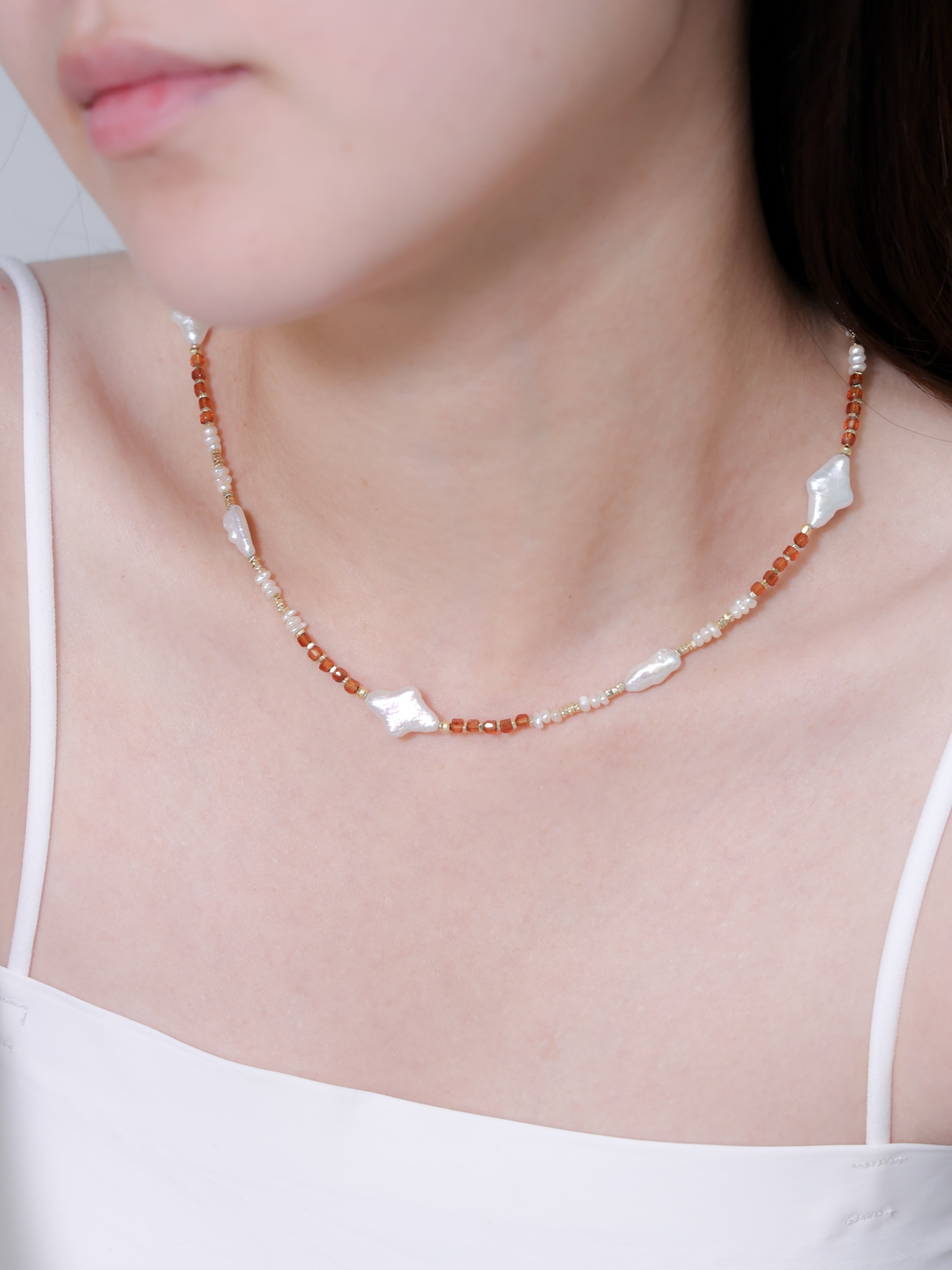 オレンジガーネット ネックレスの着用イメージ。白いトップスに映える、温かみのあるオレンジとホワイトパールの組み合わせ。