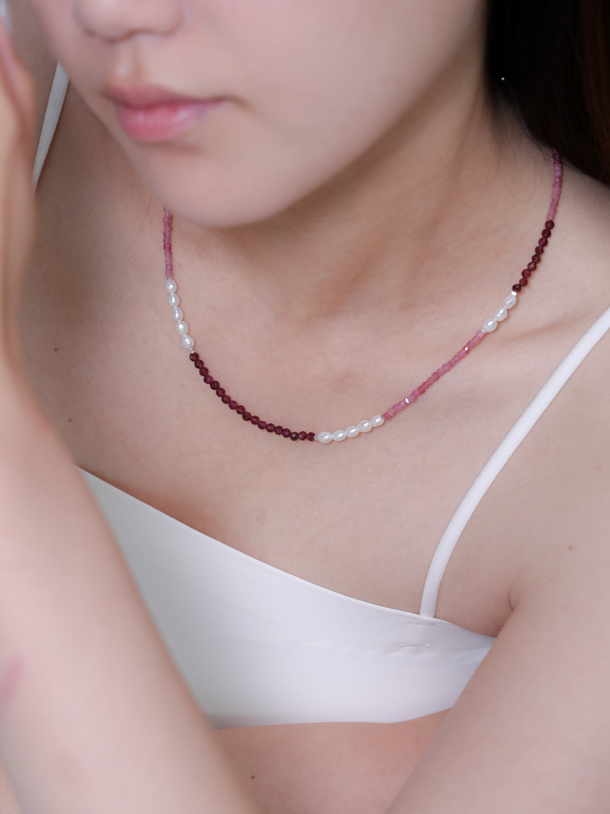 伏し目がちのモデル写真。ガーネットの深い赤色が、大人の女性の落ち着きと情熱を表現するコーディネート。