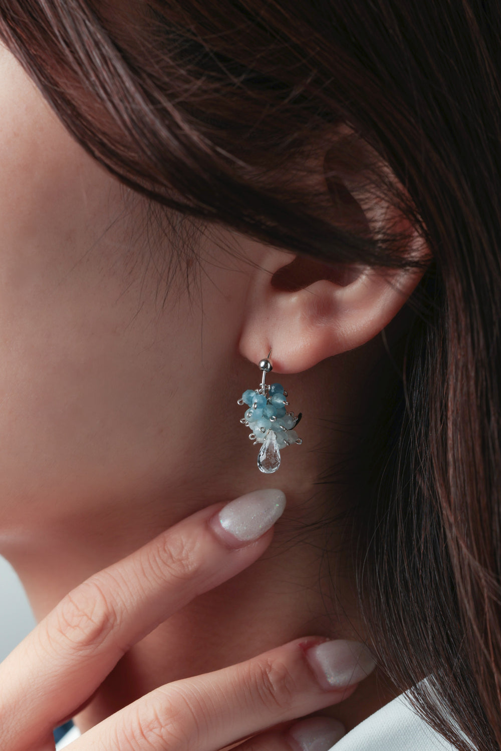 手を添えたモデルの横顔。動くたびにキラキラと輝く「揺れるピアス」は、上品で華やかな印象を与えるスタイル。