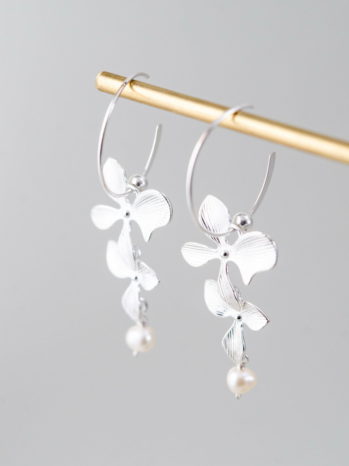 2連フラワー & 淡水パール フープピアス - 【風に舞う花】。テクスチャー加工された2つのメタルフラワーと淡水パールが揺れる、SV925製フープピアス（シルバー）。