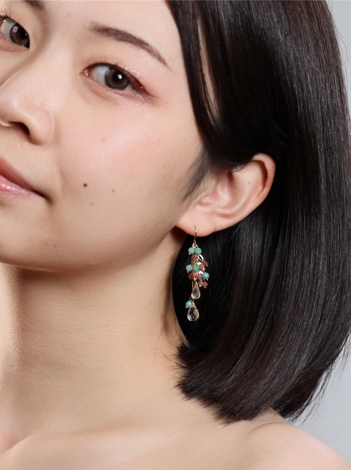 耳もとで揺れる水色と桃色のピアス