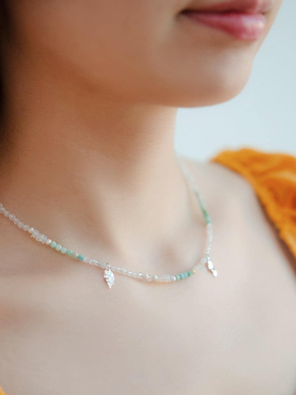 ネックレス着用 イエローのトップスと爽やかなブルーのコントラスト