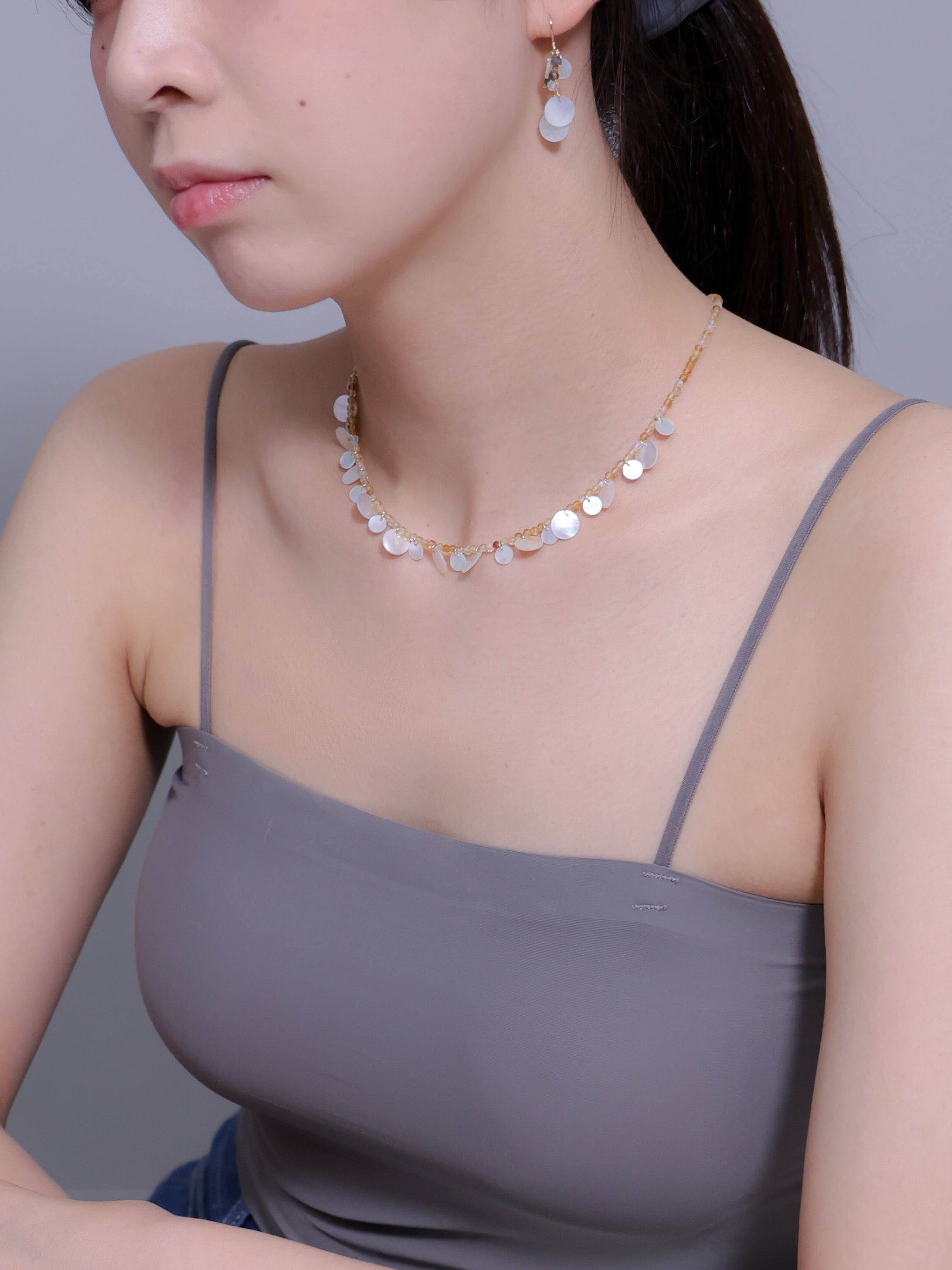 シトリンネックレス着用 横顔 グレーのトップスに映える黄色と白