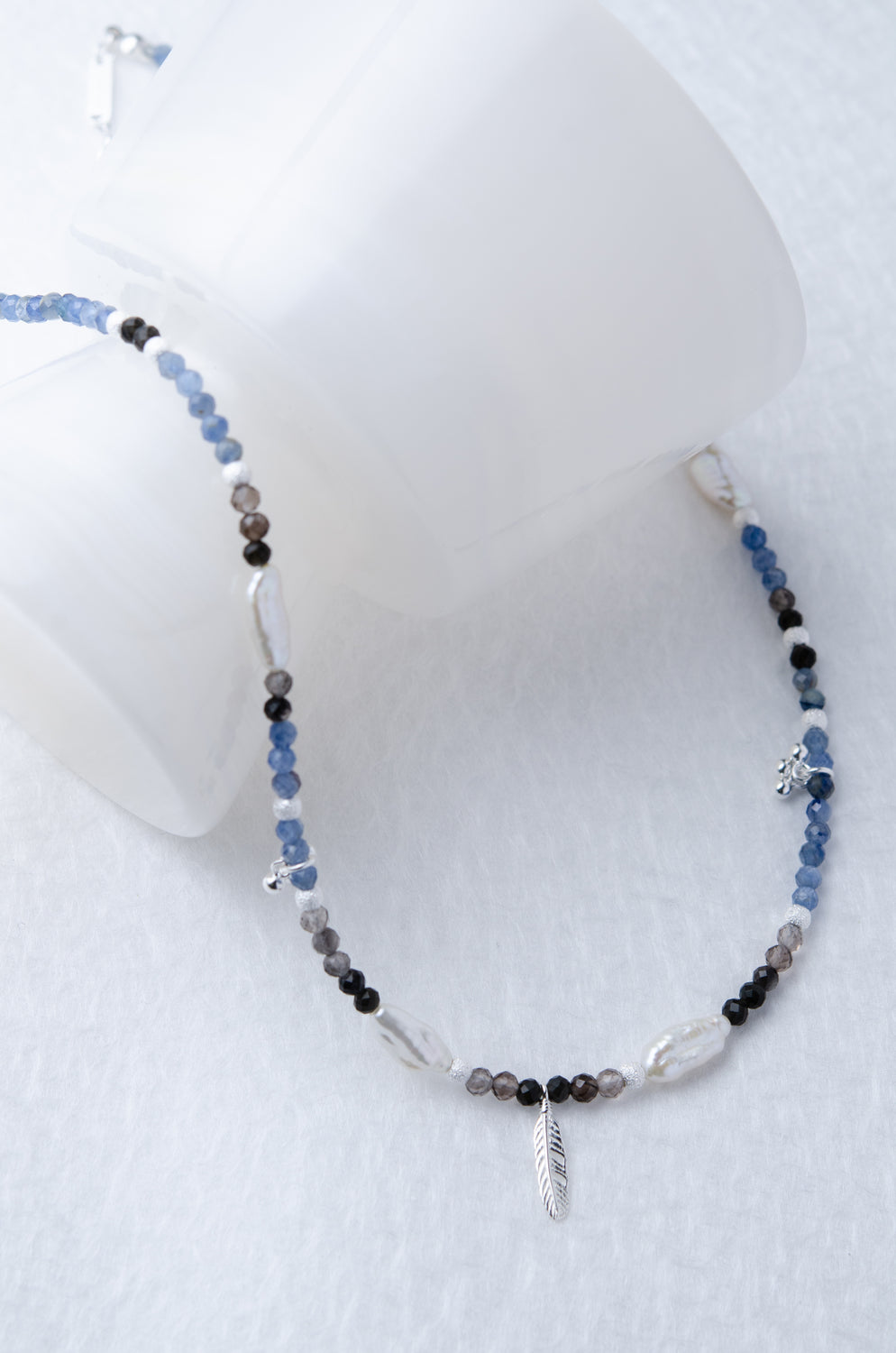 多種天然石ネックレス 白い円柱を使ったシンプルなディスプレイ