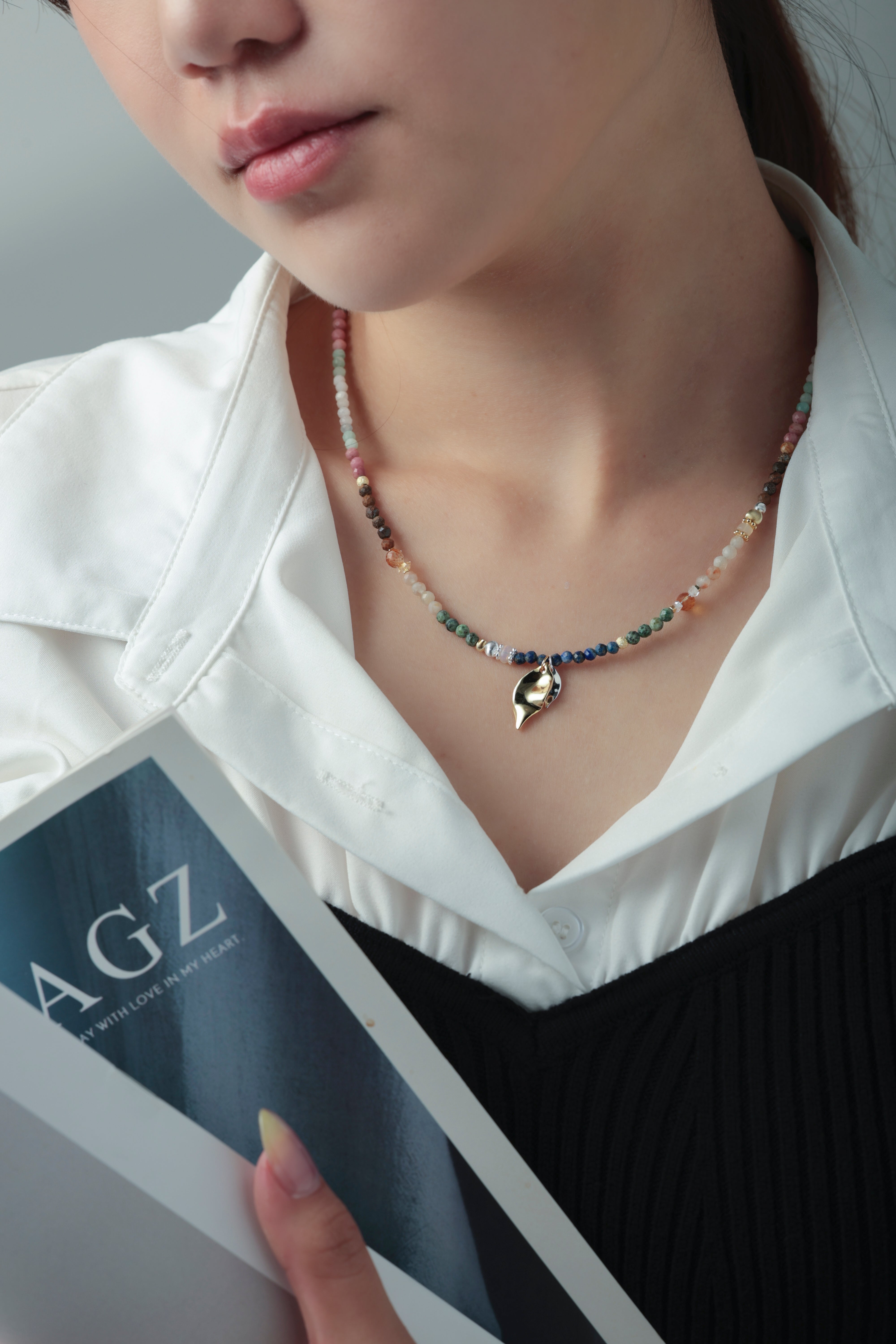 天然石ネックレス着用 白シャツコーデ 雑誌を持つ女性 ライフスタイル画像