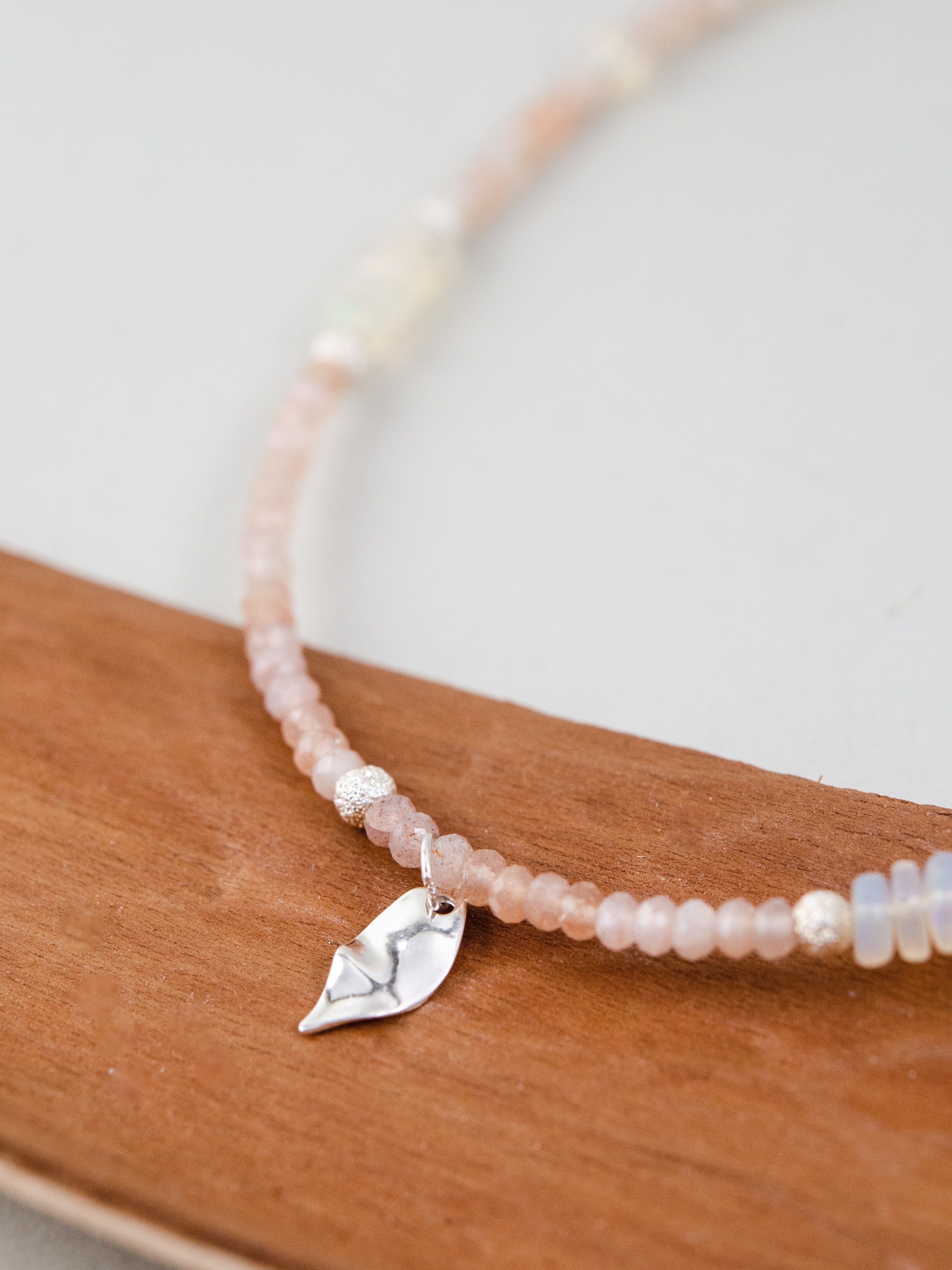 オパールとサンストーンのビーズ詳細 木の背景と調和するナチュラルな質感